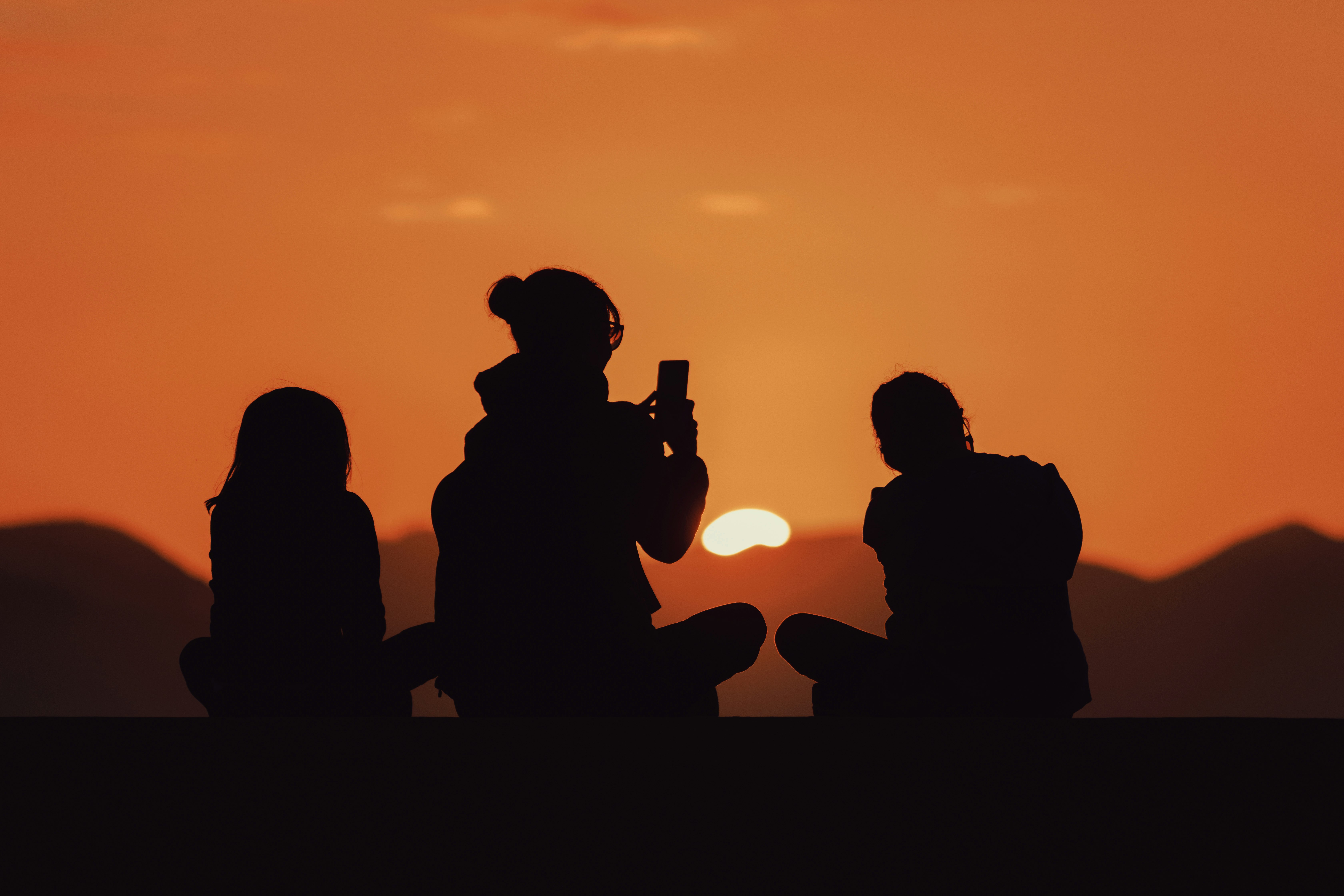 silhouette of people sitting on bench during sunset